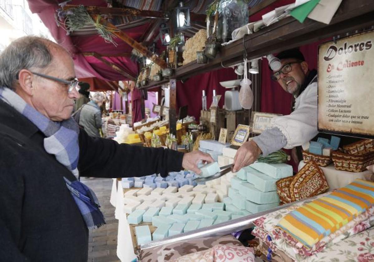 Un comerciante ofrece sus productos a un jubilado en una feria rural.