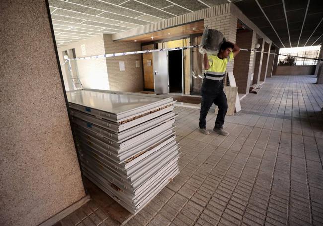 Un operario sale del portal, junto a las nuevas puertas de las viviendas.