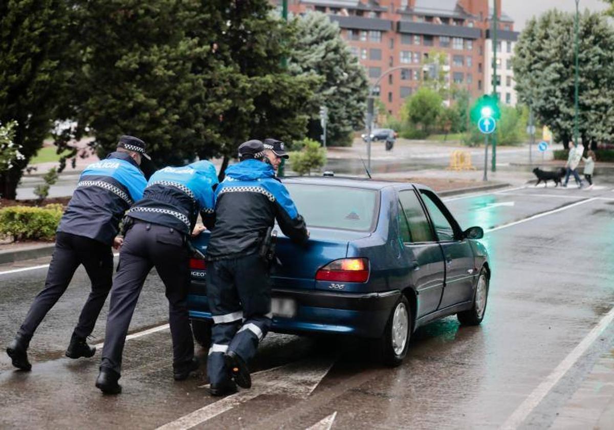 Los policías empujan un coche parado por el agua acumulado en la calle Padre José Acosta en la tarde del domingo.