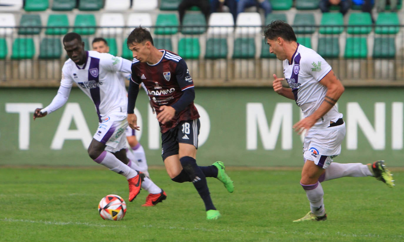 Dani Plomer conduce el balón ante la mirada de dos jugadores del Numancia.