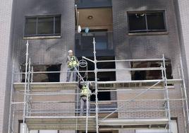 Dos operarios instalan la semana pasada un andamio frente a la fachada del edificio afectado.