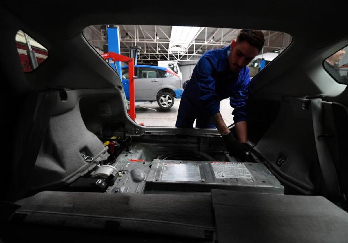 Un alumno de mecánica para coches híbridos y eléctricos accede a las baterías de un turismo.