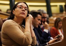 Una diputada se pone el pinganillo durante una sesión plenaria, en el Congreso de los Diputados.