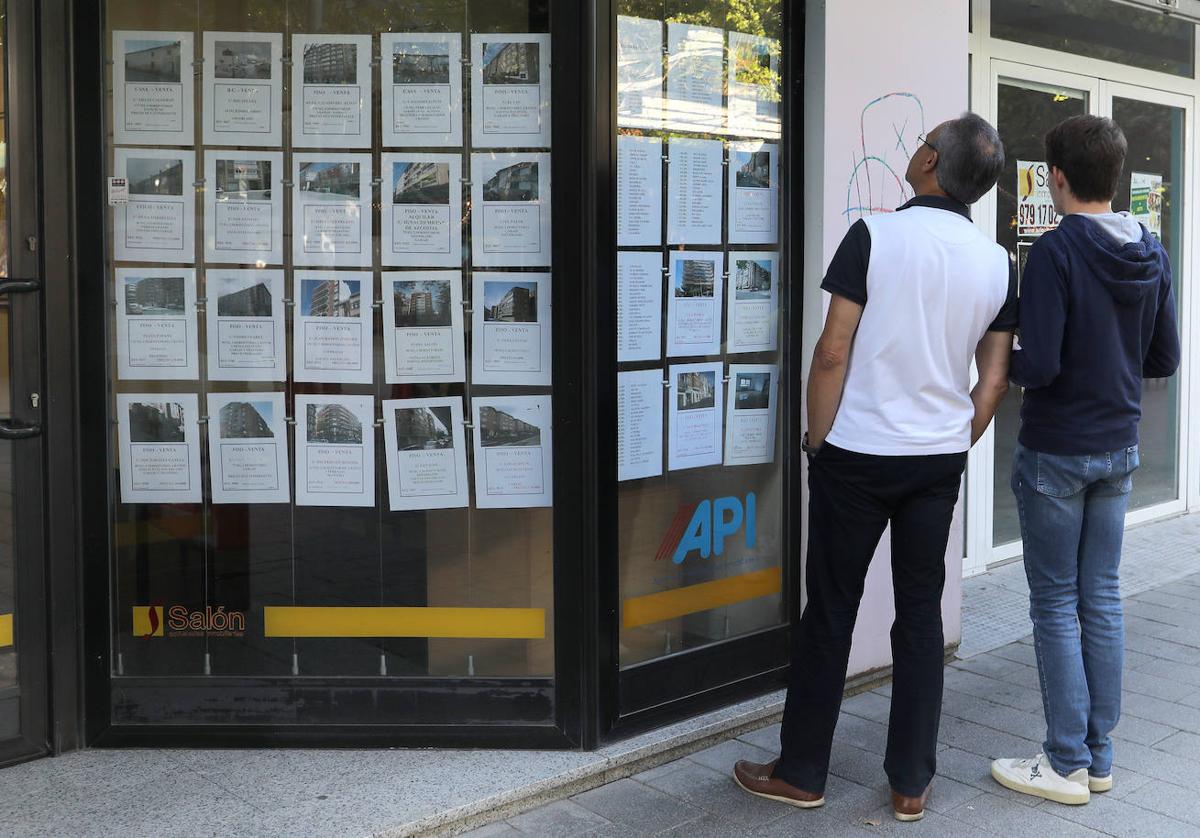 Un hombre observa los carteles de pisos en el escaparate de la inmobiliaria Salón.