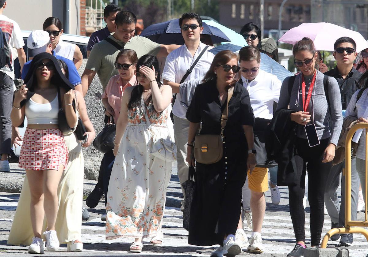 Un grupo de personas camina por la ciudad con paraguas para resguardarse del sol.