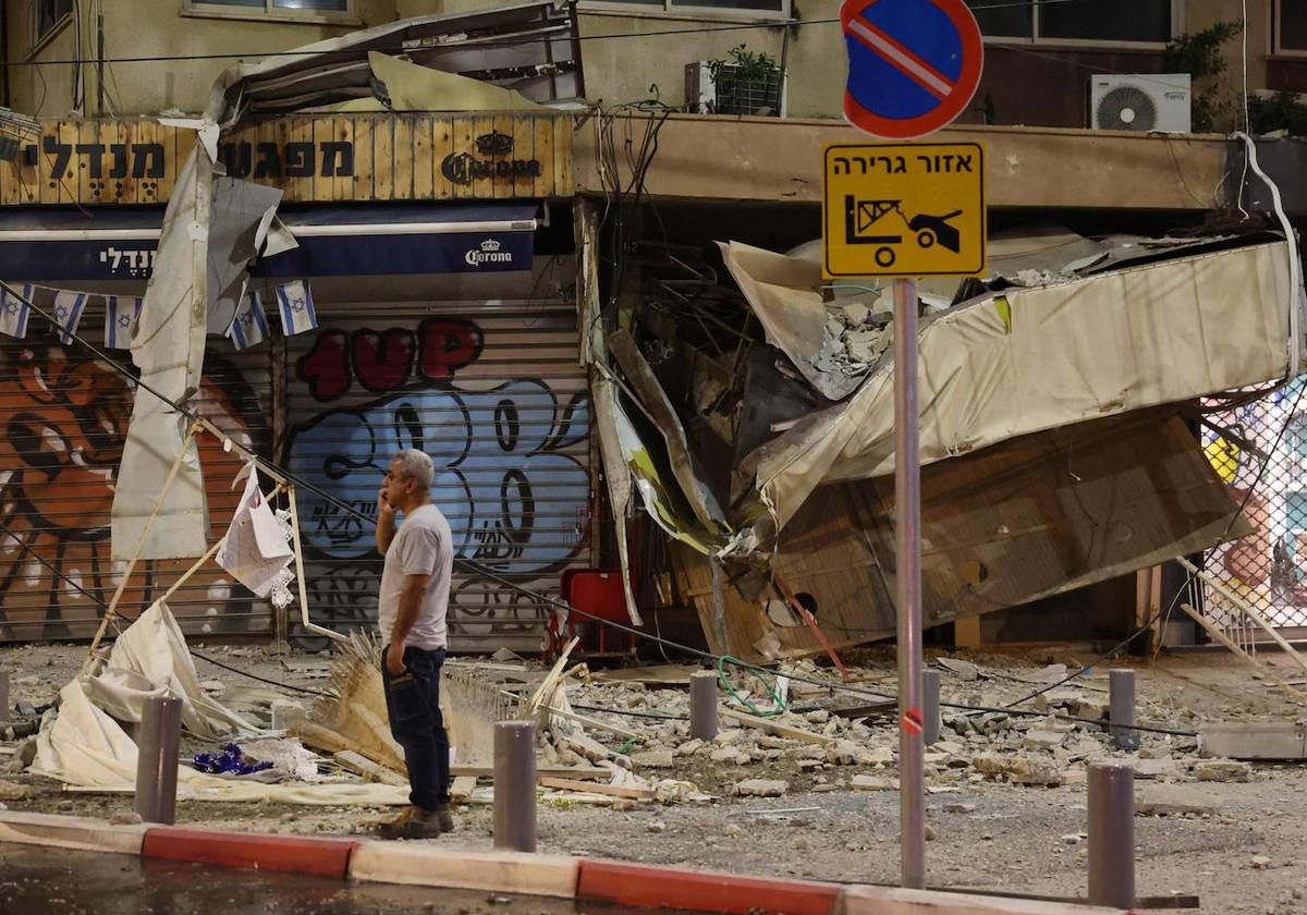 Un hombre habla por teléfono junto a un edificio bombardeado.