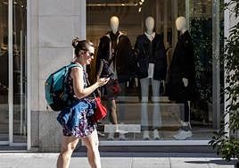 Una mujer pasea ante un escaparate que muestra ropa de abrigo en la calle Santiago.