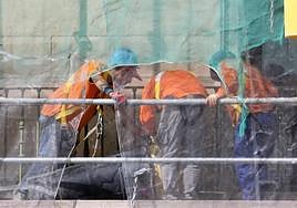 Tres trabajadores de la construcción subidos en un andamio.