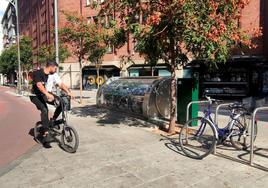 Un ciclista pasa junto al Parkibici de Doctrinos y junto a un estacionamiento al aire libre.