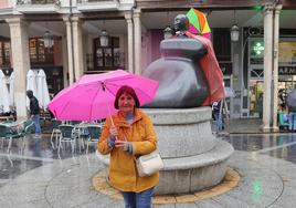 Paula González posa con un paraguas rosa delante de la estatua de la Mujer Palentina.