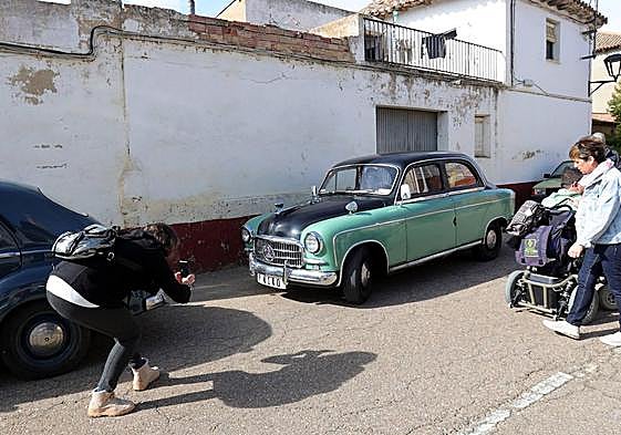 Una mujer fotografía uno de los coches clásicos en Husillos este domingo.
