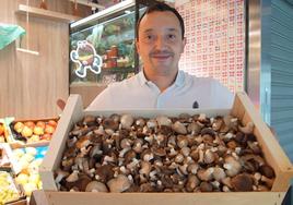 Óliver Porro muestra una caja de setas cardo en su frutería en el Mercado del Val de Valladolid.