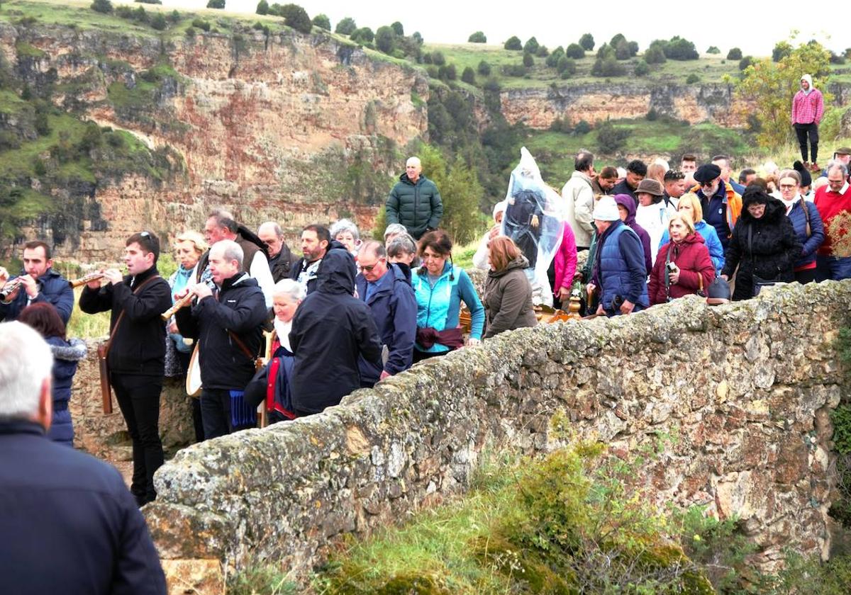 Multitud de personas participan en la procesión en la ermita de San Frutos, con la imagen del patrón protegida de la lluvia con un plástico.