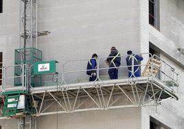 Obreros en un andamio trabajando en el exterior de un edificio en construcción.