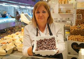 Yolanda Sánchez muestra un cuenco de uvas pasas en su puesto del Mercado del Val de Valladolid.