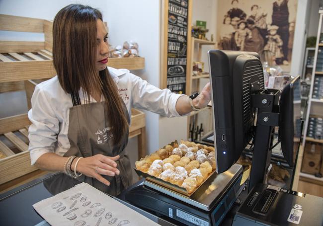 Una trabajadora de una pastelería pesa los buñuelos típicos de la festividad.