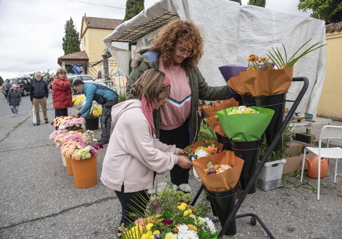 Una florista y una niña, en la venta de ramos y centros funerarios frente al cementerio de Segovia.