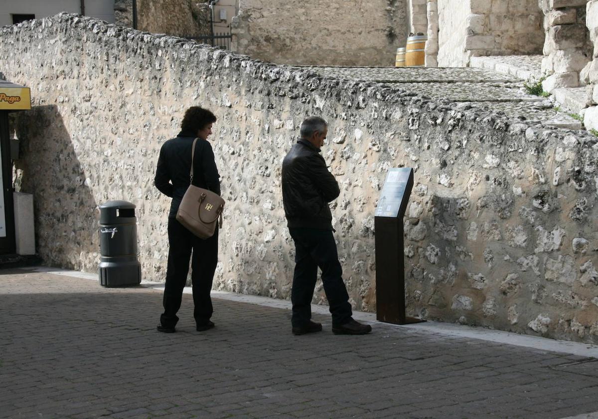 Dos personas observan un cartel turístico en Cuéllar.