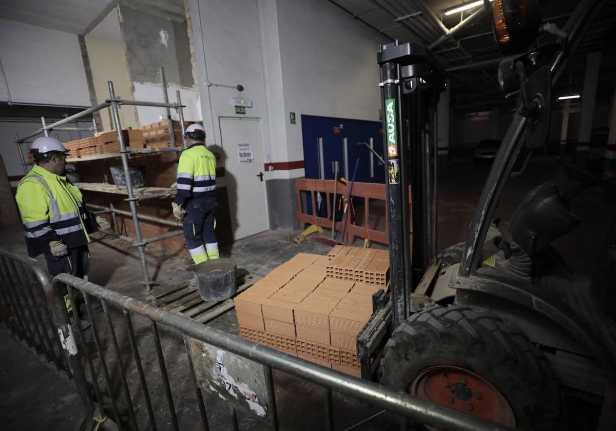 Dos operarios trabajan en la ampliación de las escaleras que van del aparcamiento al mercado.