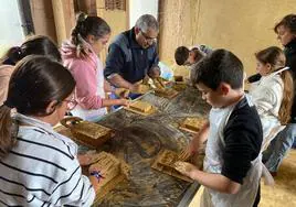 Participantes en los talleres junto con un tutor dan forma al barro.