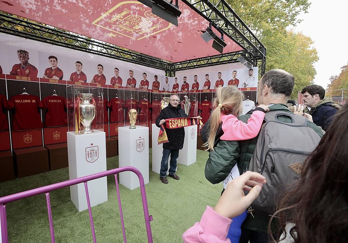 Un aficionado sujeta una bufanda de la selección mientras se fotografía con los títulos.