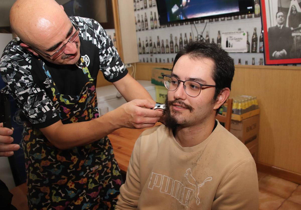 Miguel Ángel Senovilla, del bar La Gaviota, afeita a Iván Gómez, uno de sus clientes.