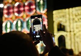 Una mujer graba con su teléfono móvil el espectáculo de luces de la plaza de Portugalete.