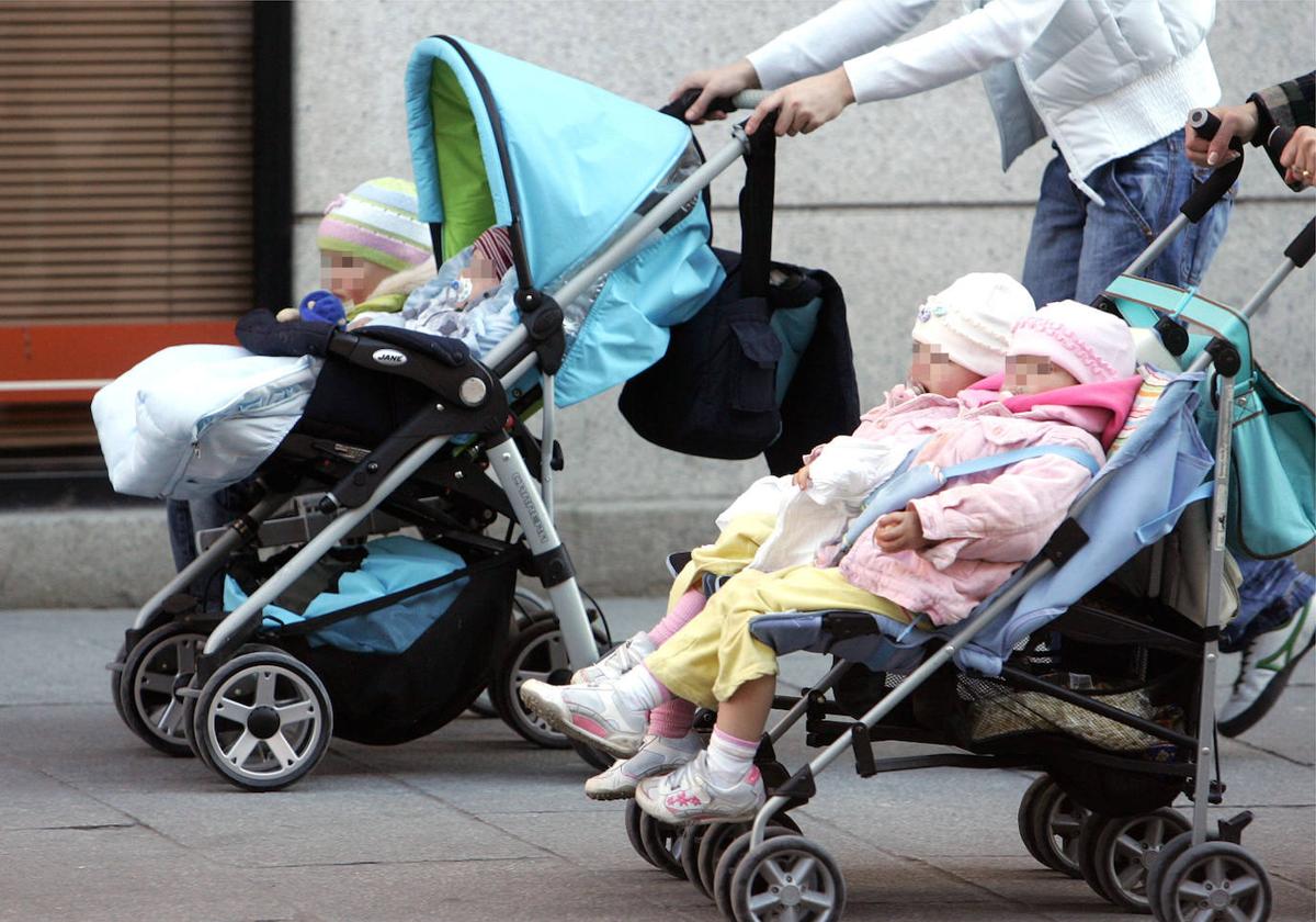 Unos padres llevan a sus hijos en unos carritos de bebé por el centro de Segovia.