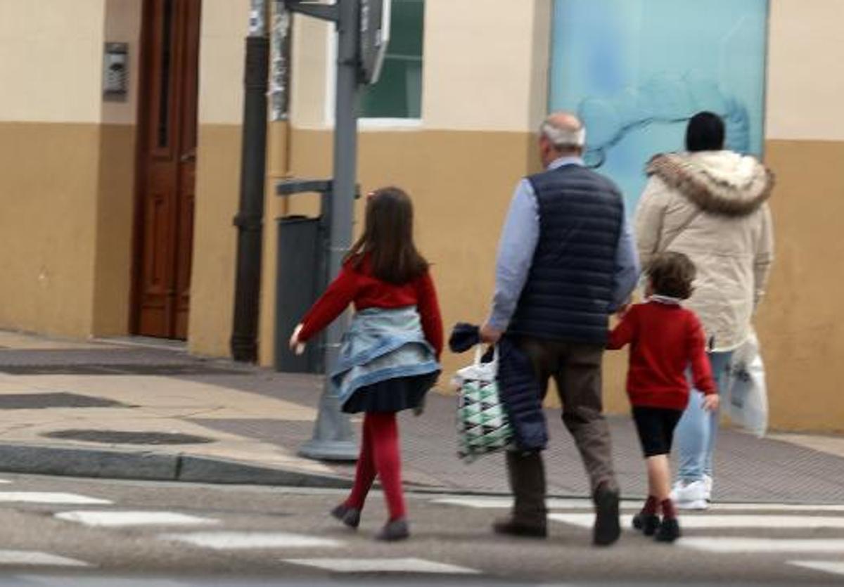 Un abuelo con sus nietos a la salida del colegio.