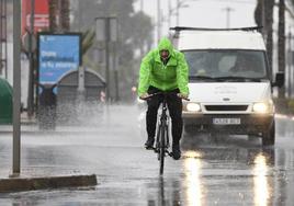 Un hombre pedalea bajo la lluvia.