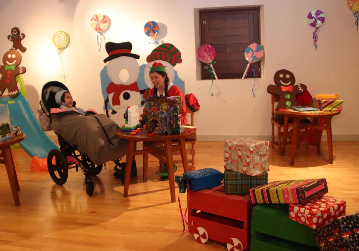 Una ayudante de Papá Noél junto a una niña en la Casa de la Ilusión de Cuéllar.