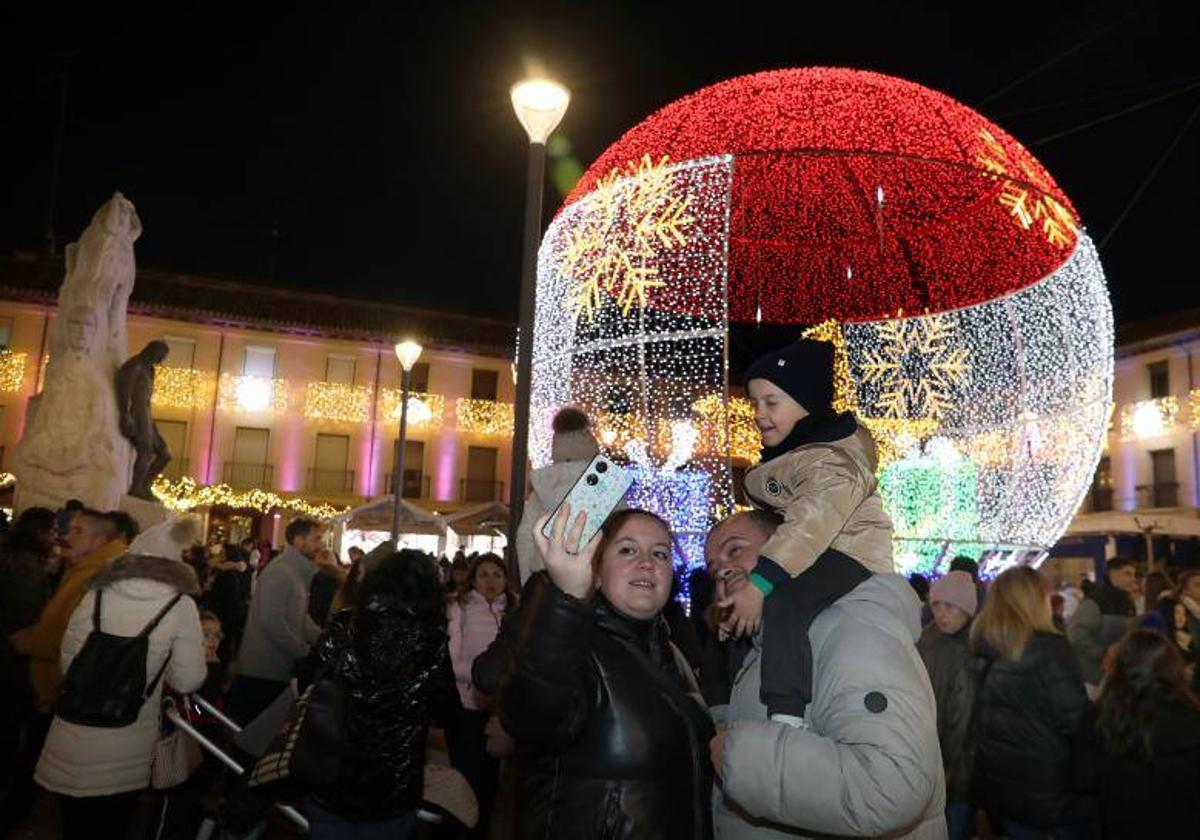 Una familia se fotografía con la gran bola de luz de la Plaza Mayor.