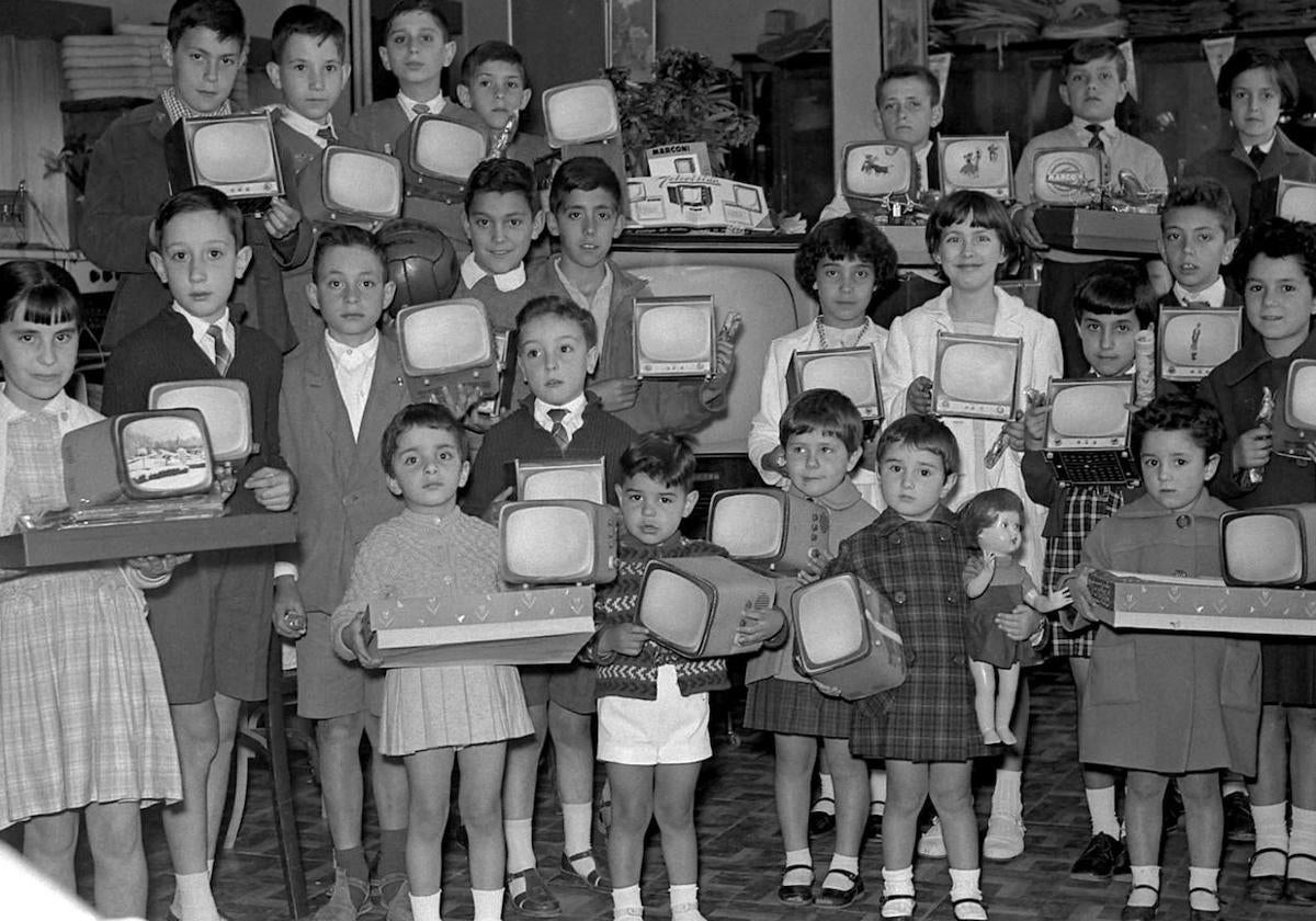 Un grupo de niños segovianos muestra televisores Marconi de juguete hacia 1959.