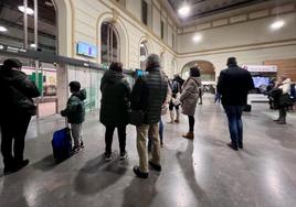 Varias personas esperan y miran las pantallas informativas de la Estación del Campo Grande con las incidencias de este lunes.