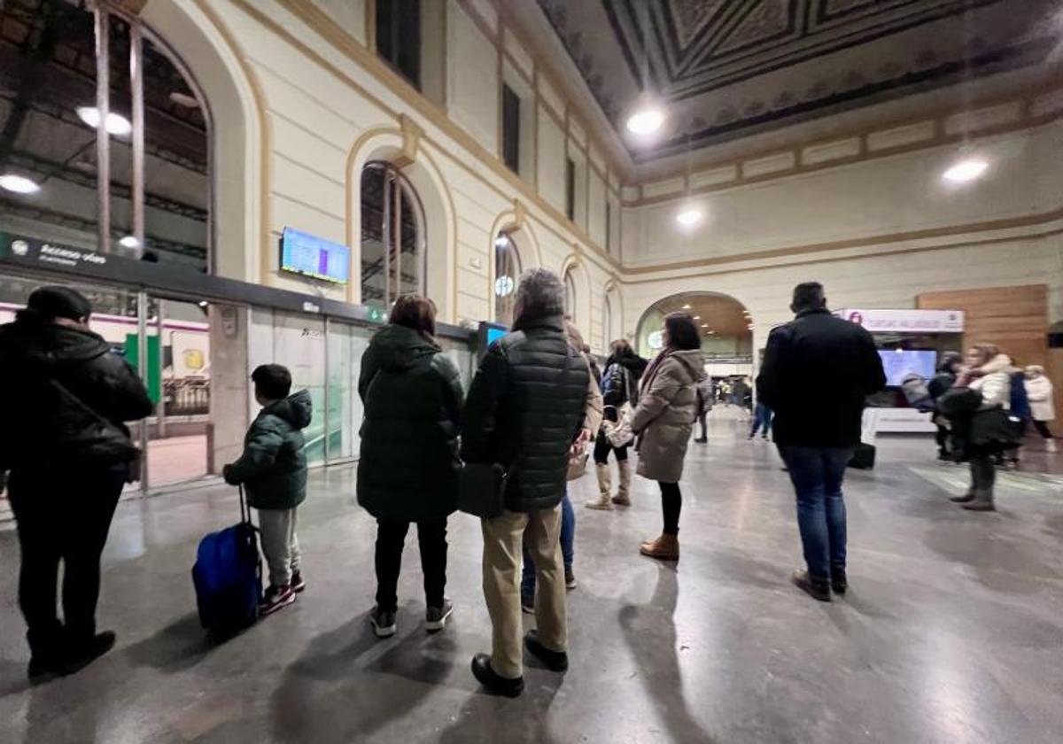 Varias personas esperan y miran las pantallas informativas de la Estación del Campo Grande con las incidencias de este lunes.