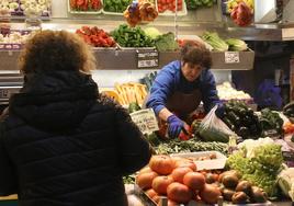 Una frutera despacha a una clienta en la ciudad de Segovia.