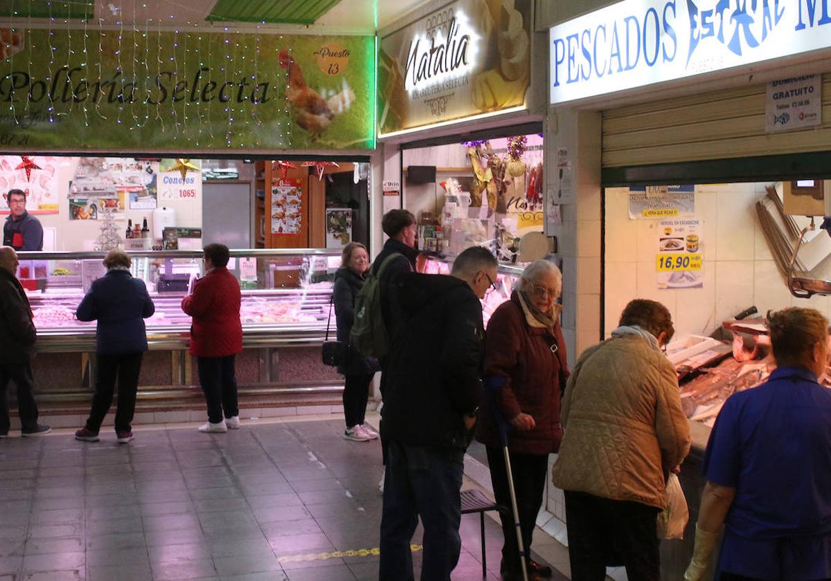 Varios clientes compran ingredientes para sus cenas navideñas en el mercado de La Albuera, este martes.