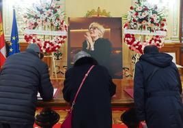 Tres personas firman en el libro de condolencias en el salón de recepciones del Ayuntamiento.