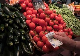 Una consumidora paga una compra en el Mercado de la Mercé, en Barcelona,