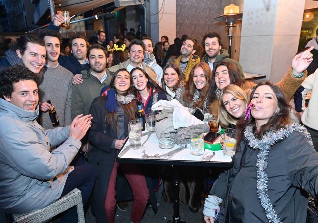 Un gran grupo de amigos celebra la tardebuena. En la mesa, de color verde, la sartén reconvertida en funda de teléfono móvil con el dispositivo pegado.