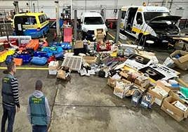 Dos agentes de la Guardia Civil junto al material y los vehículos incautados.