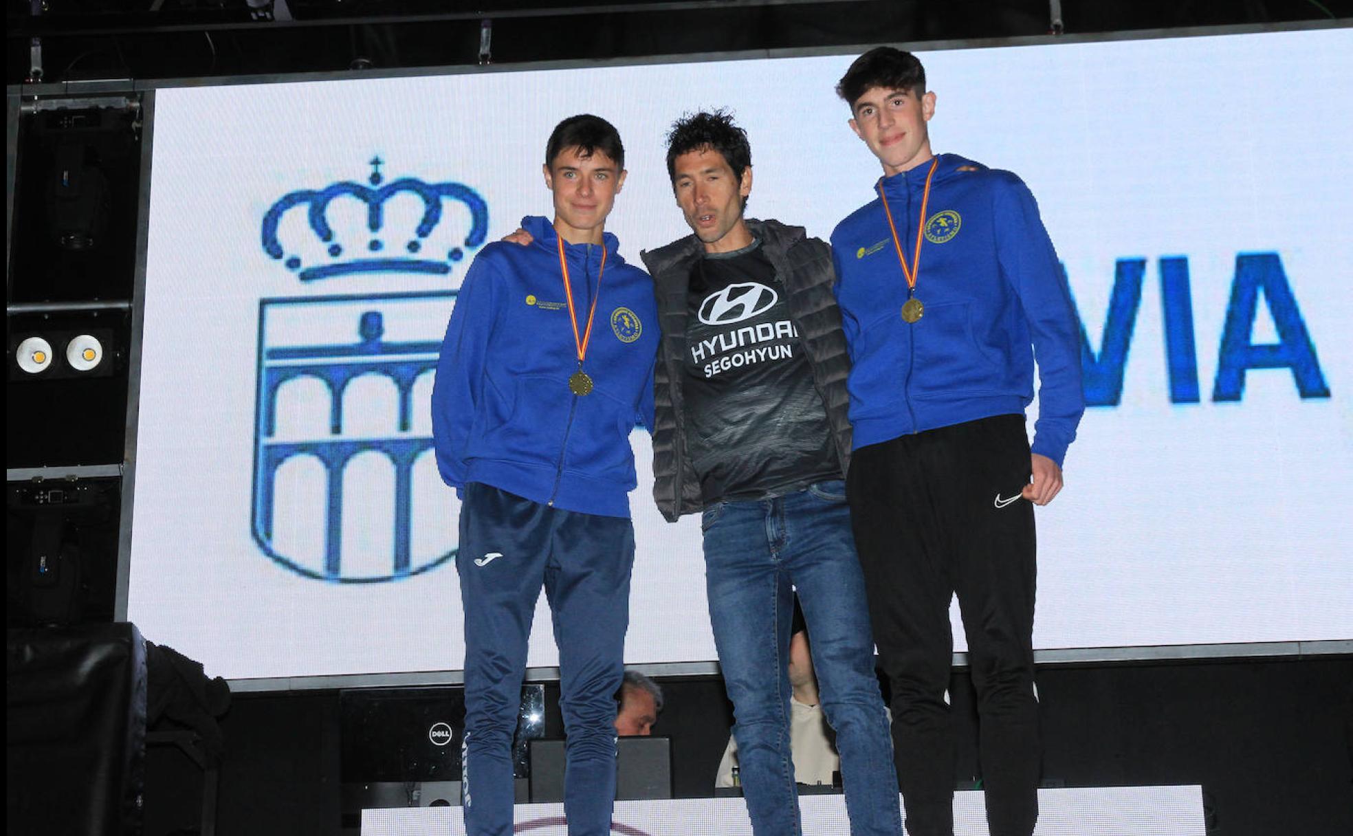 Javi Guerra flanqueado por dos corredores con sus medallas. 