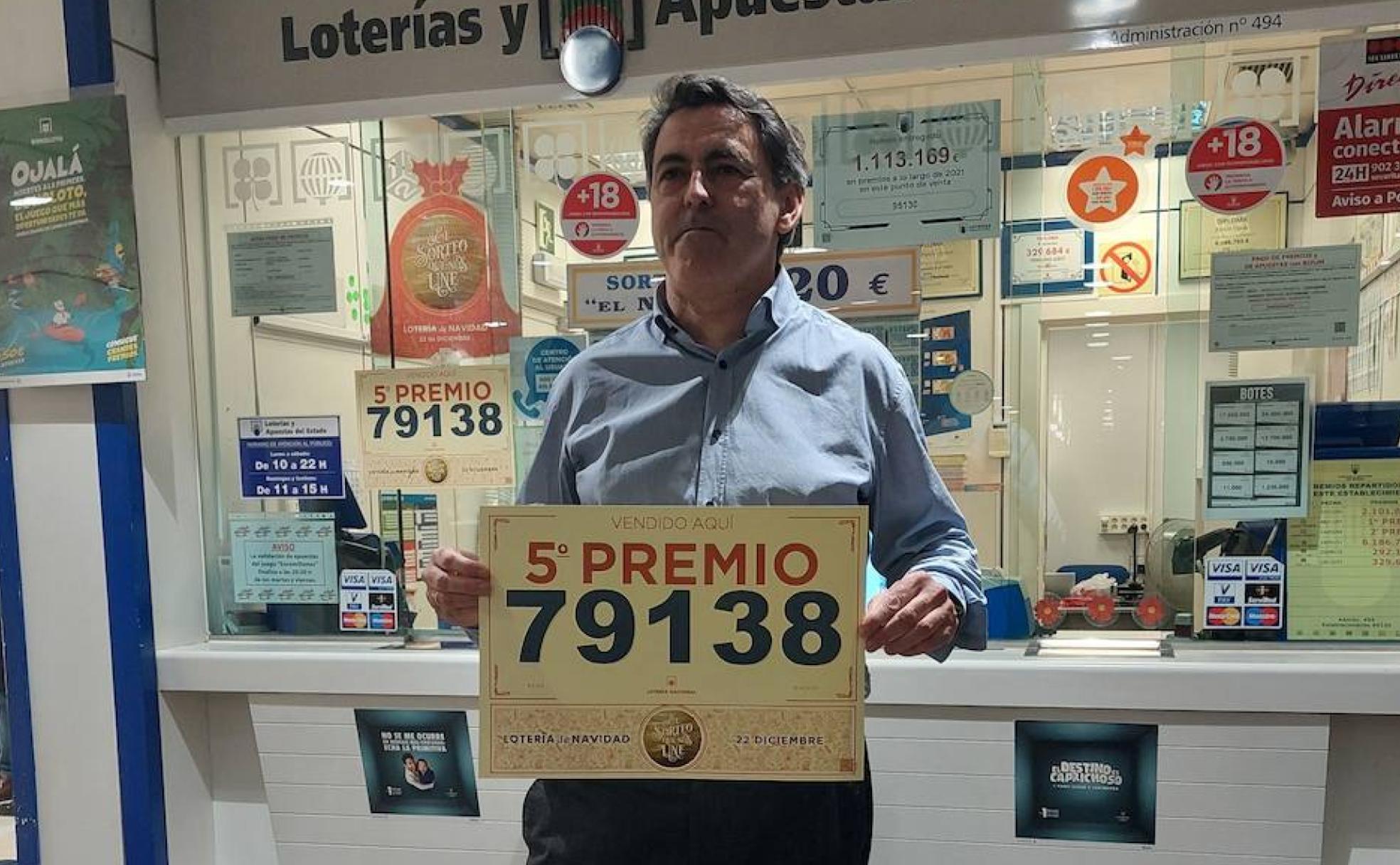 El segoviano Francisco Ceballos muestra el cartel con el número premiado que vendió en su administración en Madrid. 