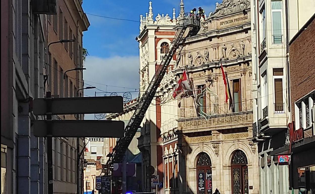 Los bomberos ascienden con la escala para colocar sacos de arena y evitar que se desprendan más placas de uralita. 