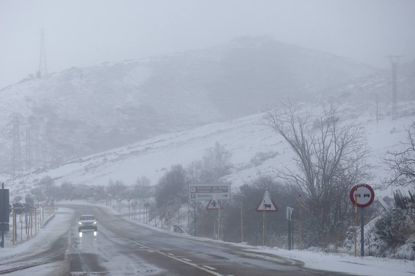 Un coche circula por una carretera nevada en la provincia de León.