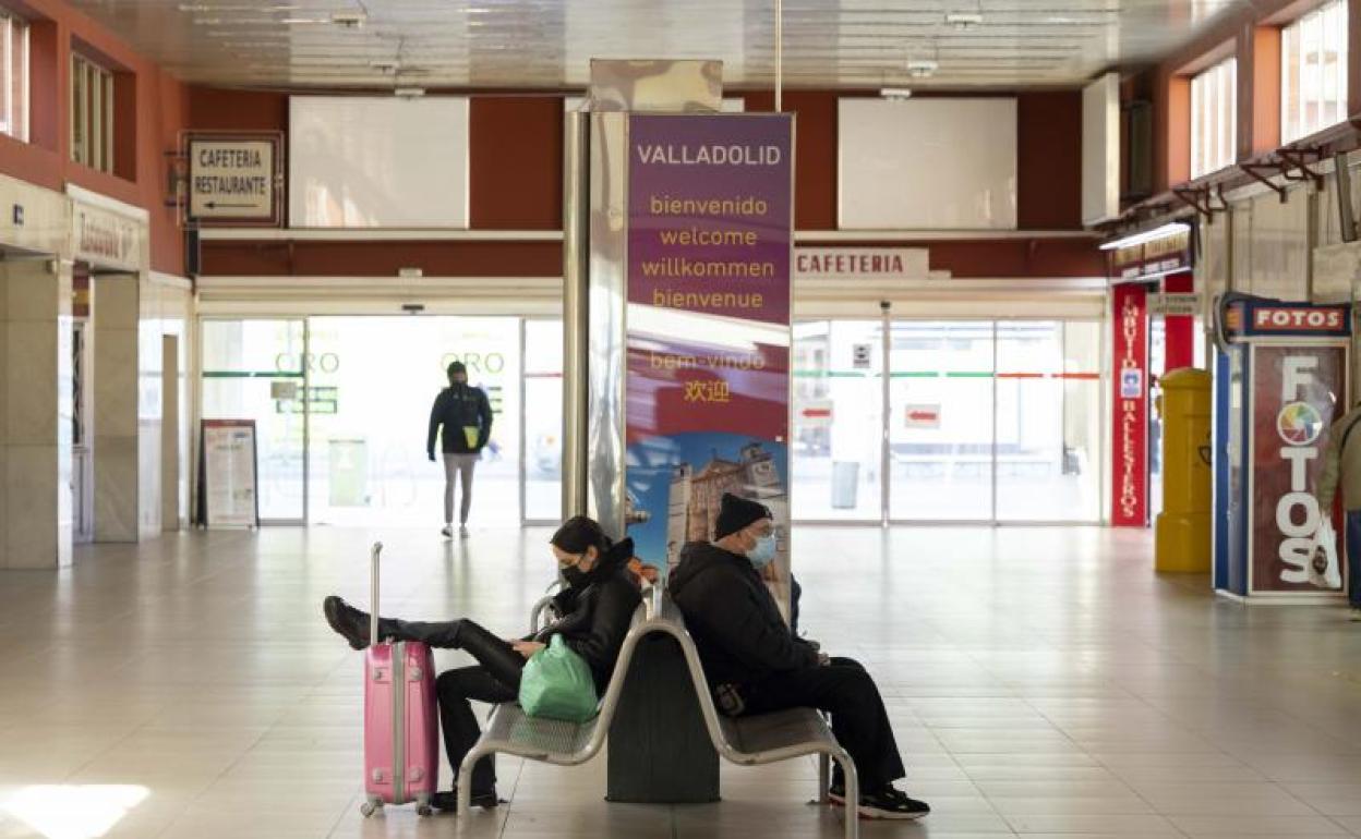 Varios viajeros esperan en el vestíbulo principal de la estación de Valladolid. 