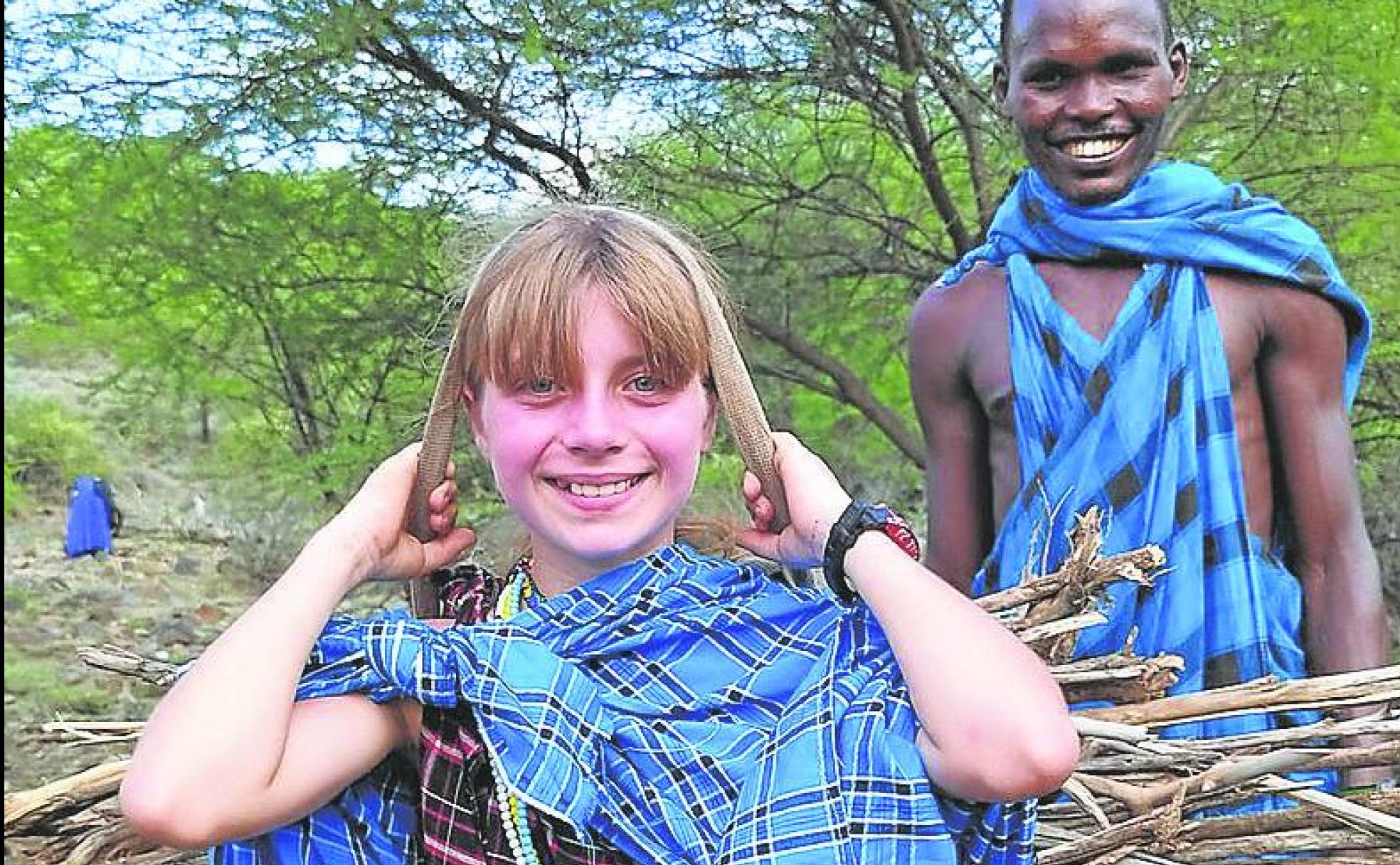 Elvia porta unos haces de leña junto a un masai. 