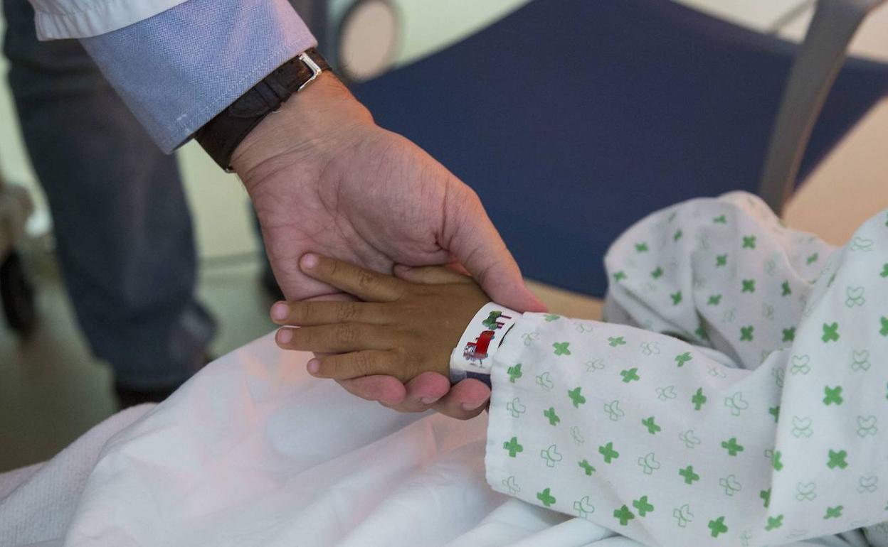 Un doctor acaricia la mano de un paciente infantil terminal en el Hospital Río Hortega.