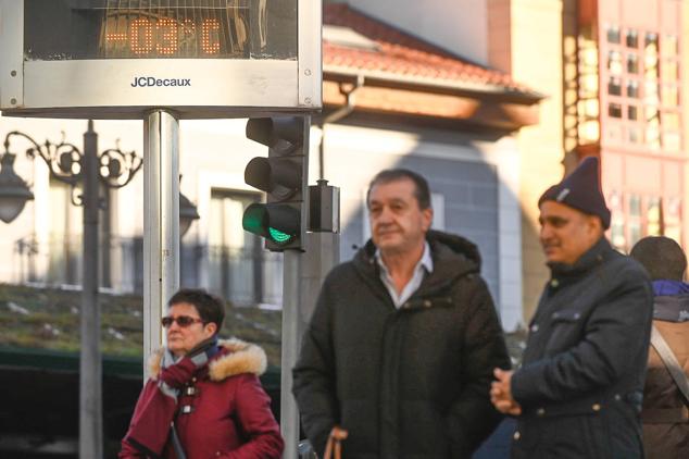 Viandantes fuertemente abrigados caminan en Plaza España mientras el termómetro marca tres grados bajo cero.