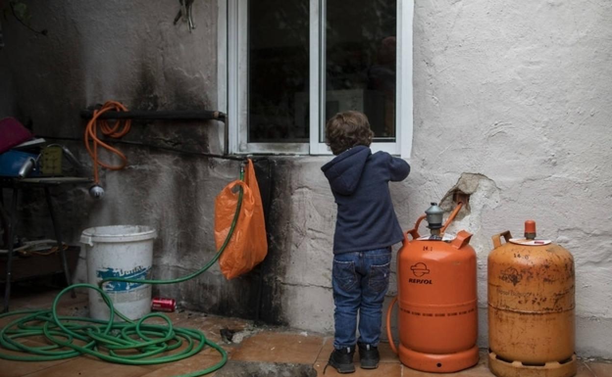 Un niño juega junto a unas bombonas de butano